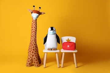 Obraz premium Toys with face masks and first aid bag on yellow background. Pediatrician practice