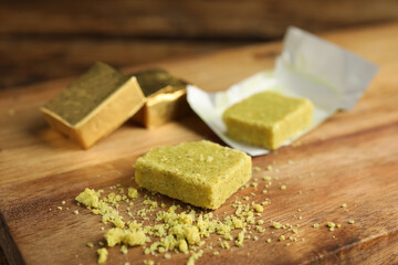 Bouillon cubes and crumbles on wooden board, closeup