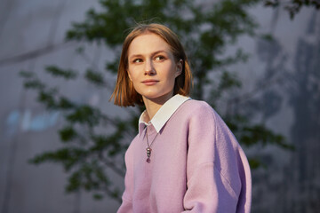 Portrait of young woman student near university building. Female intern professional outside...