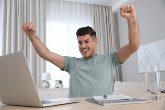 Emotional man participating in online auction using laptop at home