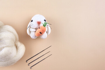 Felted handmade bunny near the skein of wool and needles.