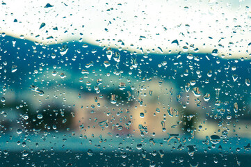Naklejka na ściany i meble Rain drops on window glasses surface with sunset. drops on glass spray on window background for dark text view selective focus