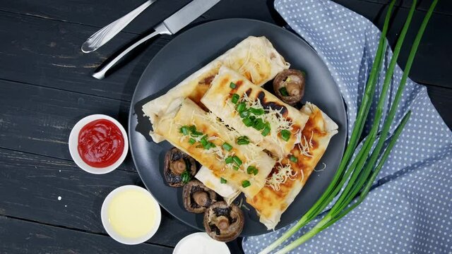 resh roll of thin lavash or lavash stuffed with potatoes, mushrooms, cheese, carrots, sauce, herbs on a plate.