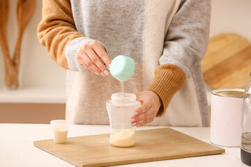 Woman preparing baby milk formula in kitchen