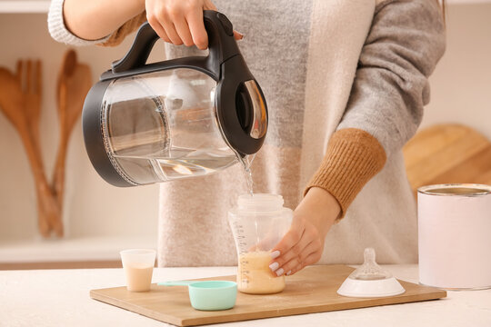 Woman Preparing Baby Milk Formula In Kitchen