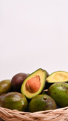 Whole and half avocado in a weaved basket.
