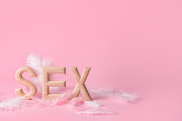 Word SEX with feathers on color background