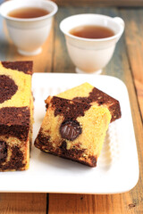 Tea Time with Slice of Marble Travel Cake, Square Cake with Melted Chocolate on the Center. Served on White Plate