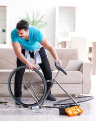 Fototapeta na wymiar Young man repairing bicycle at home