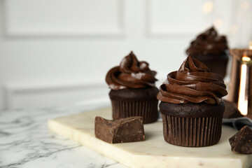 Delicious chocolate cupcakes with cream on white marble table. Space for text