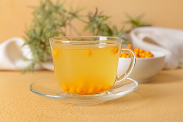 Cup of healthy sea buckthorn tea on color background