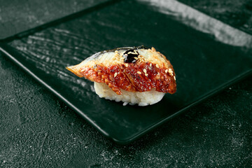 Nigiri sushi with eel on a black board with ginger and wasabi. Japanese kitchen. Food delivery. Black background