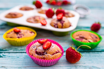 Delicious muffins with fresh strawberry fruits on a wooden background.