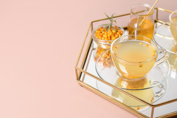 Tray with healthy sea buckthorn tea in cup on color background