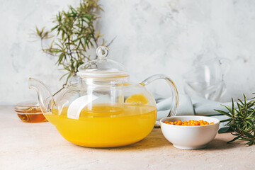 Teapot of healthy sea buckthorn tea on table