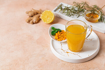 Cup of healthy sea buckthorn tea on color background