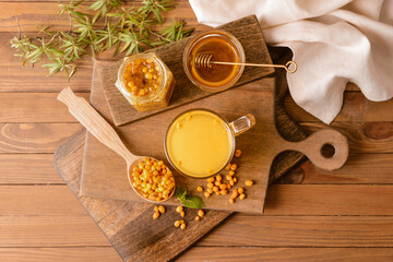 Cup of healthy sea buckthorn tea with honey on table
