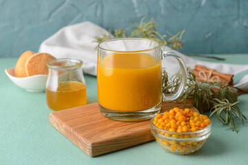Cup of healthy sea buckthorn tea on color background