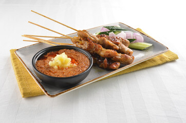 Bbq grilled chicken and beef satay meat stick skewer with cucumber, onion and spicy peanut gravy sauce in dark bar counter background western snack cuisine halal menu