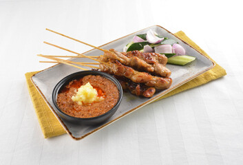 Bbq grilled chicken and beef satay meat stick skewer with cucumber, onion and spicy peanut gravy sauce in dark bar counter background western snack cuisine halal menu