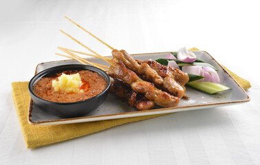 Bbq grilled chicken and beef satay meat stick skewer with cucumber, onion and spicy peanut gravy sauce in dark bar counter background western snack cuisine halal menu