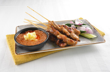Bbq grilled chicken and beef satay meat stick skewer with cucumber, onion and spicy peanut gravy sauce in dark bar counter background western snack cuisine halal menu