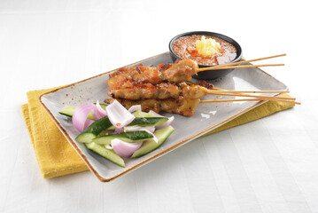 Bbq grilled chicken and beef satay meat stick skewer with cucumber, onion and spicy peanut gravy sauce in dark bar counter background western snack cuisine halal menu