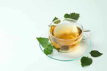 Cup of nettle tea and ingredients on white background