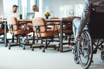 Paralyzed man in a wheelchair on the move in the disabled office building. Wheeling his way into recovery.  Businessman hand driving wheelchair. Businessman on wheelchair