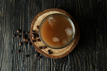 Glass of ice coffee and beans on wooden table