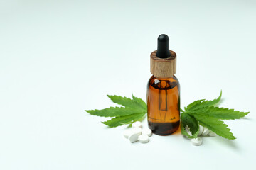 Cannabis leaves, pills and oil on white background