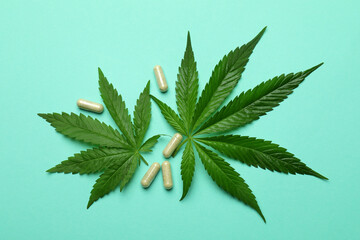 Cannabis leaves and pills on mint background