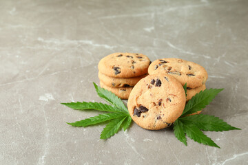 Cannabis cookies and leaves on gray textured table