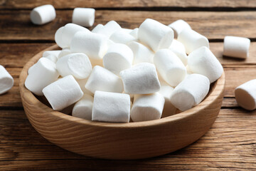 Fototapeta na wymiar Delicious puffy marshmallows on wooden table, closeup