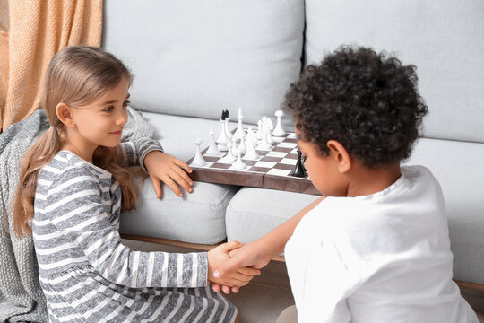 Cute children playing chess at home