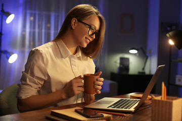 Female freelancer working at home late in evening