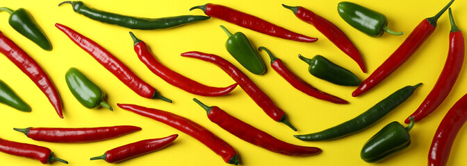 Red and green hot peppers on yellow background