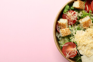 Paper bowl with Caesar salad on pink background