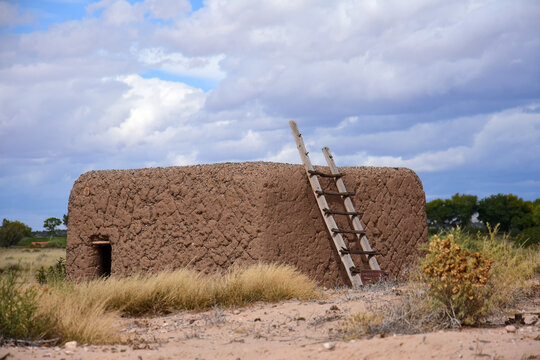an adobe kiva and ladder on a stormy day at the coronado historic site in bernalilllo, new mexico