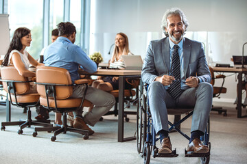 Confident and modern architect in a wheelchair, working in his office. Wheelchair businessman portrait at workplace. They're a diverse and dynamic team. Diverse Group of Colleagues