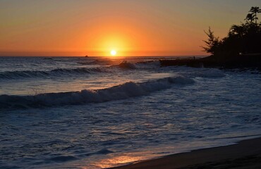 Obraz premium sunset and crashing waves in poipu, kauai, hawaii, as seen from brennecke's beach
