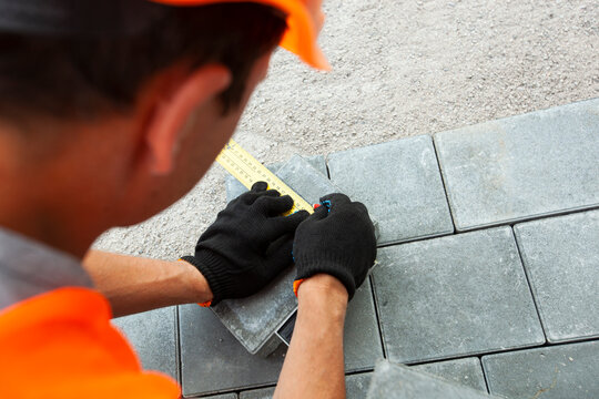 Worker lining paving slabs path