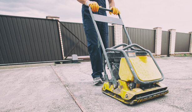 The worker tamping a gravel by the vibration plate