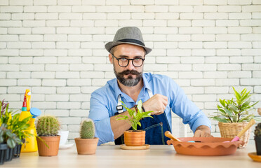 An elderly man wearing glasses is happy with tree care and decoration. It is a hobby of home gardening, living happily after retirement