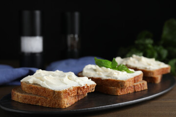 Bread with cream cheese on wooden table, closeup