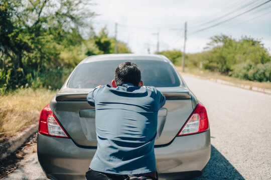 Man pushing a broken car breakdown on the road hot day. Car broken concept.