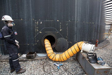 Male into the black fuel tank oil area confined space - obrazy, fototapety, plakaty