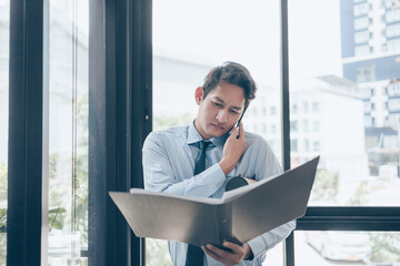 Busy businessman use mobile phone and hands hold dossier and drawing tube. Busy or a lot of work to...