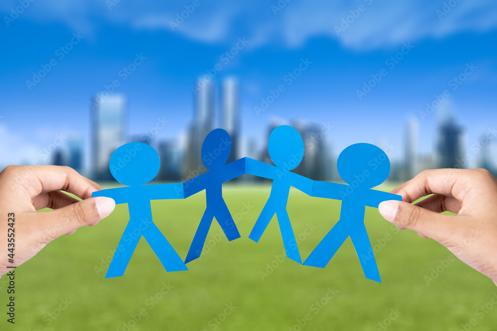 Wall mural hand holding blue people paper holding hands with cityscapes background