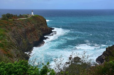 Fototapeta na wymiar picturesque kilauea lighthouse and cliff with crashing waves on a sunny day in north kauai, hawaii